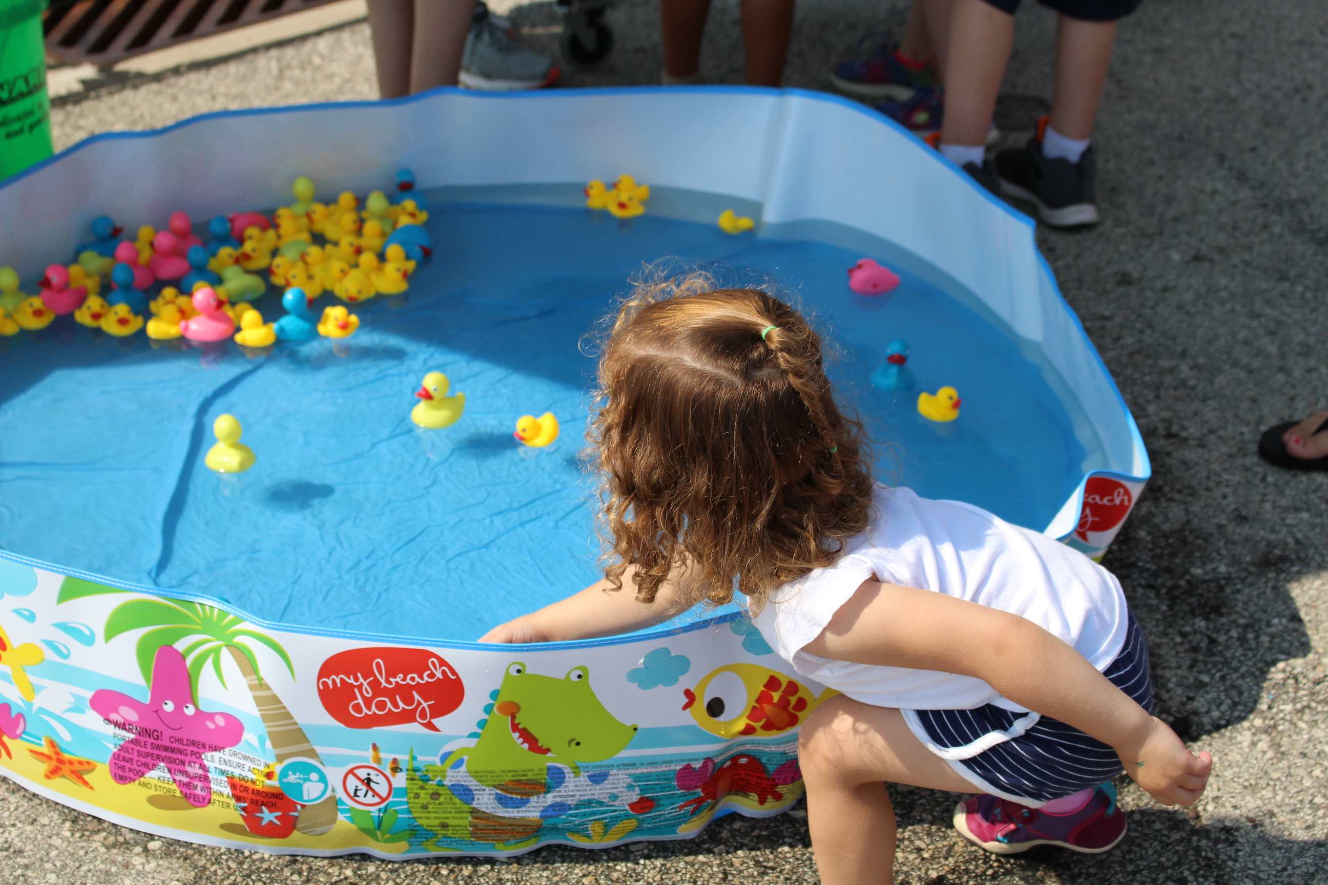 Child playing game with rubber ducks in small pool