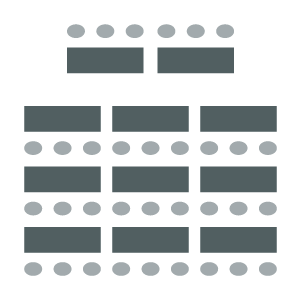 Tables arranged in rows with chairs on one side facing panel table and chairs at front of room.