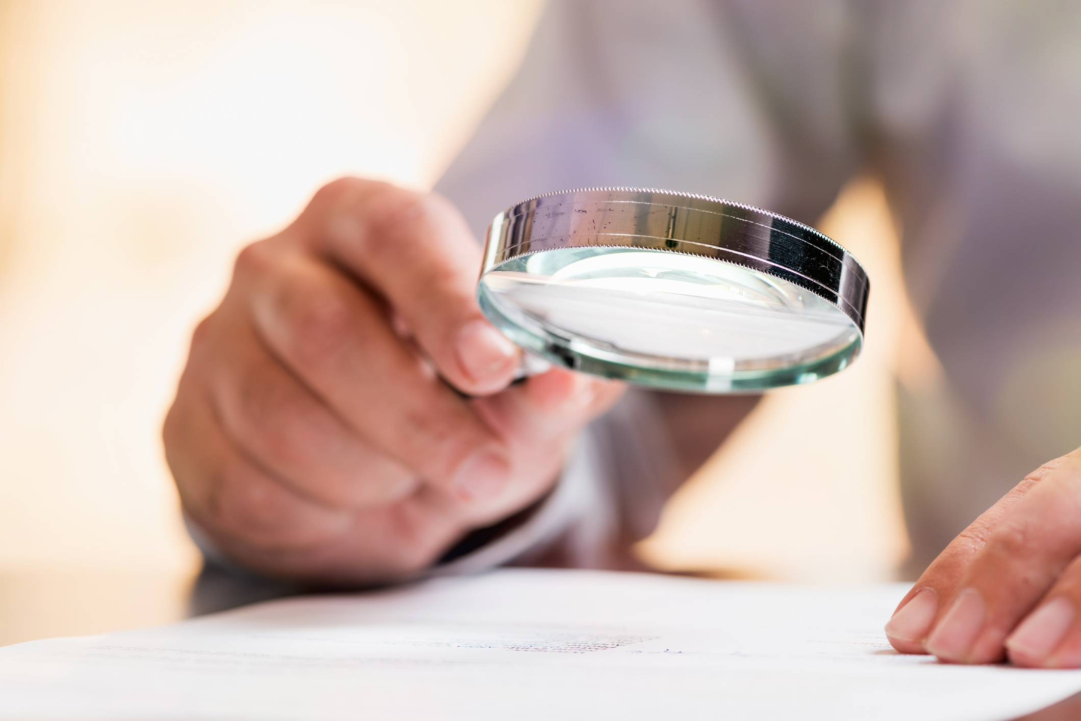 Person's hand holding magnifying glass to read