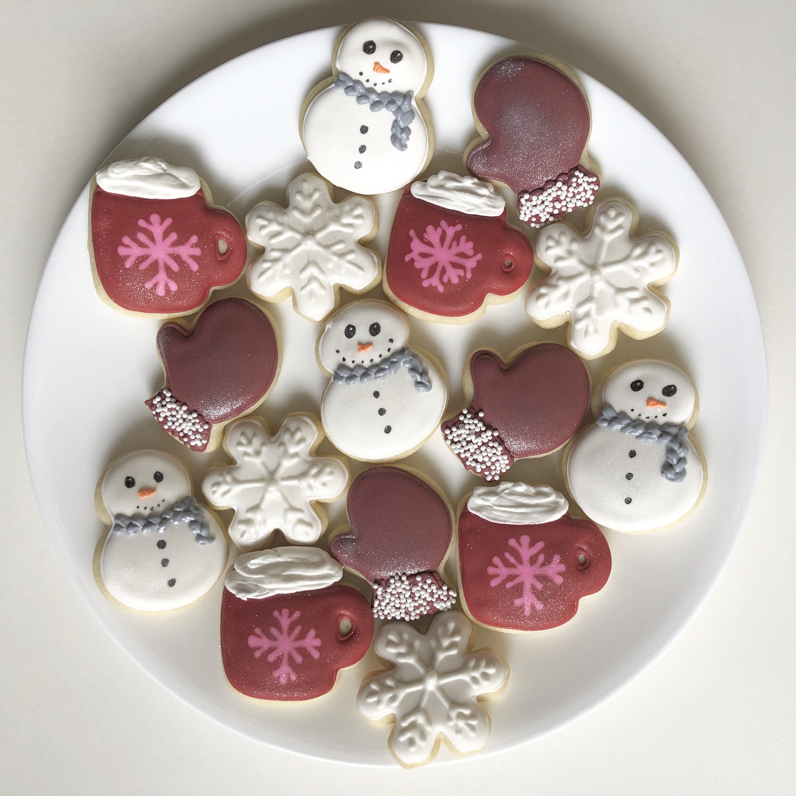 Iced sugar cookies decorated like snowmen, cocoa cups, mittens, and snowflakes