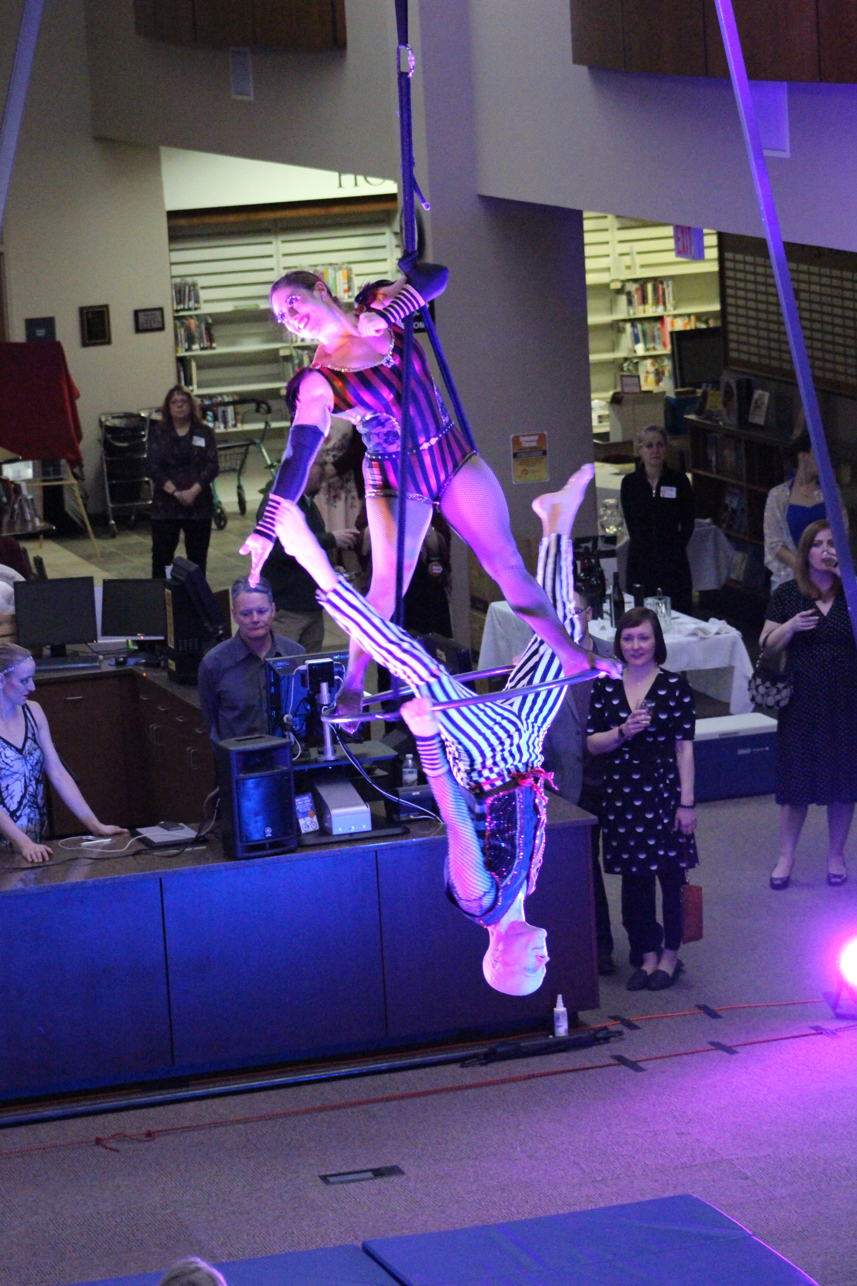 Two aerial performers suspended on ropes in front of crowd