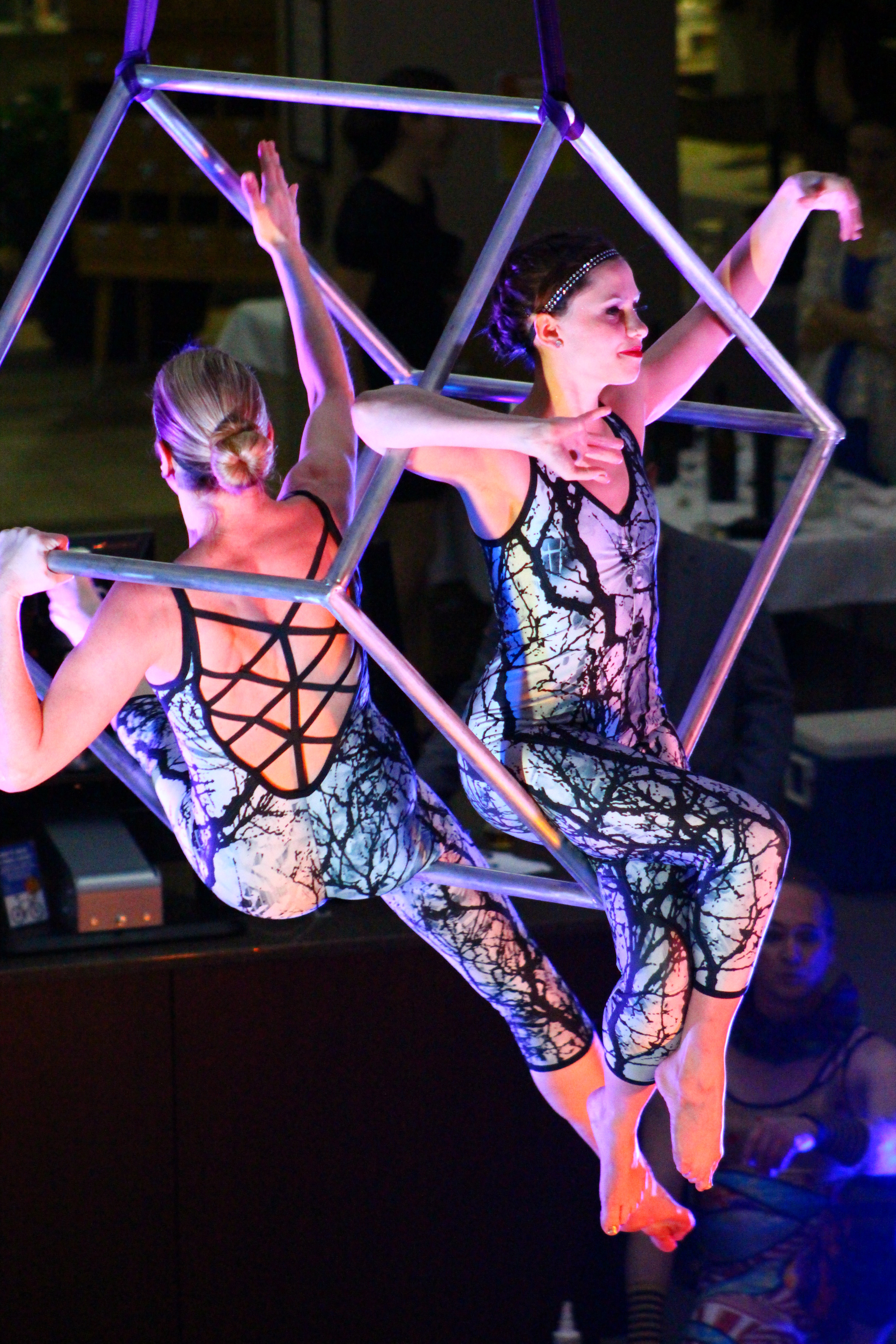 Two performers balancing in suspended cube frame