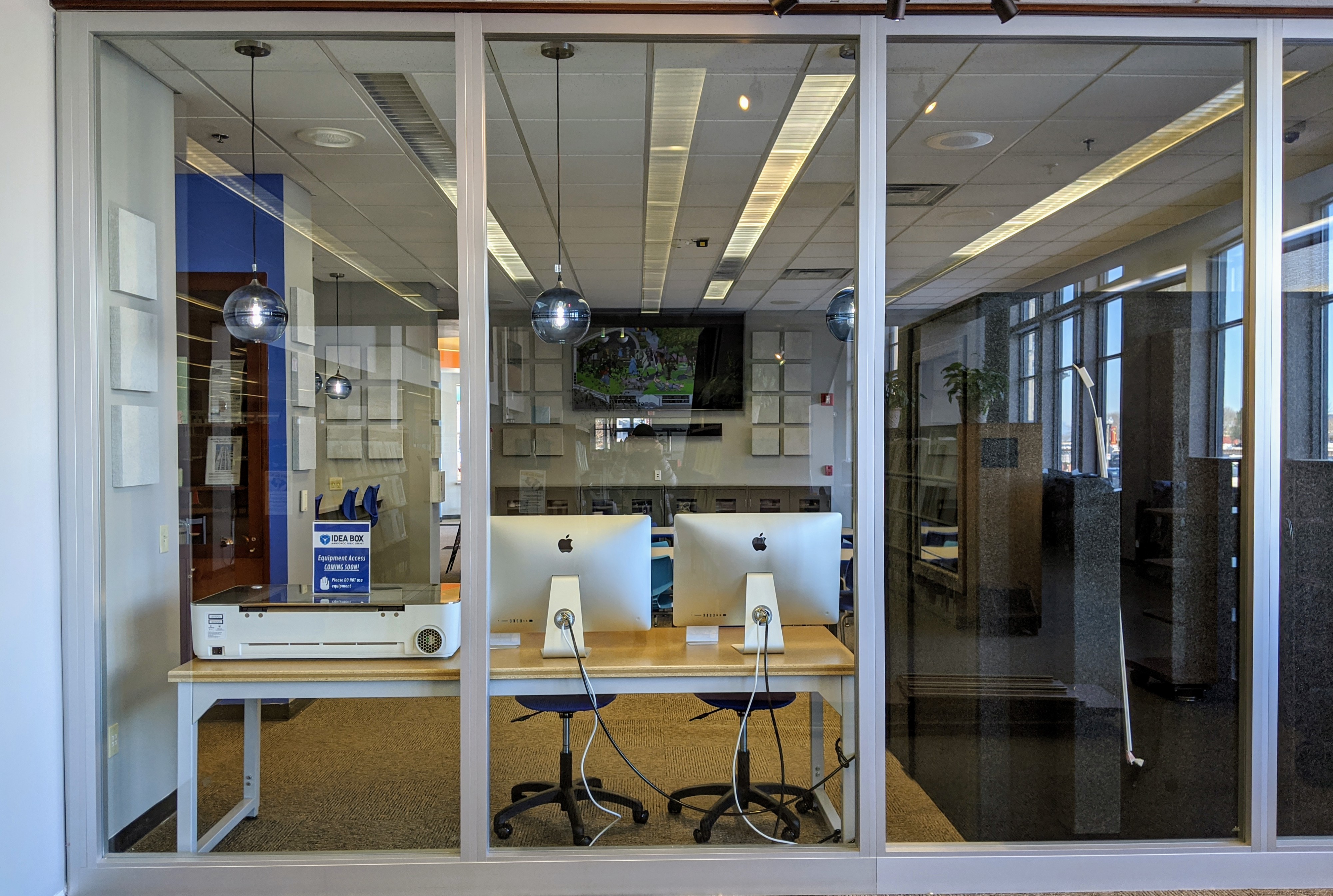 Glowforge and iMac stations taken from outside Idea Box windows