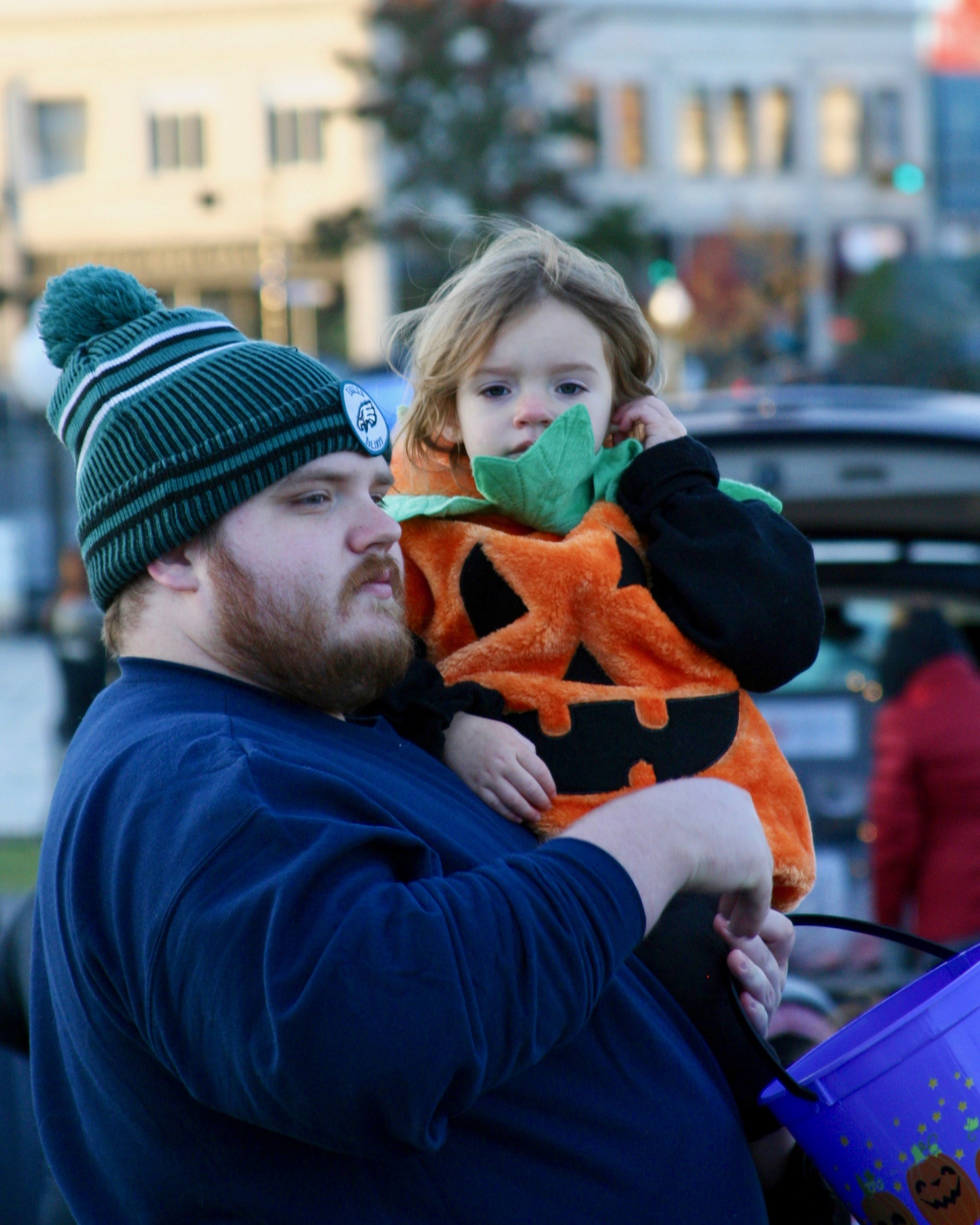 Man holding child dressed as a pumpkin