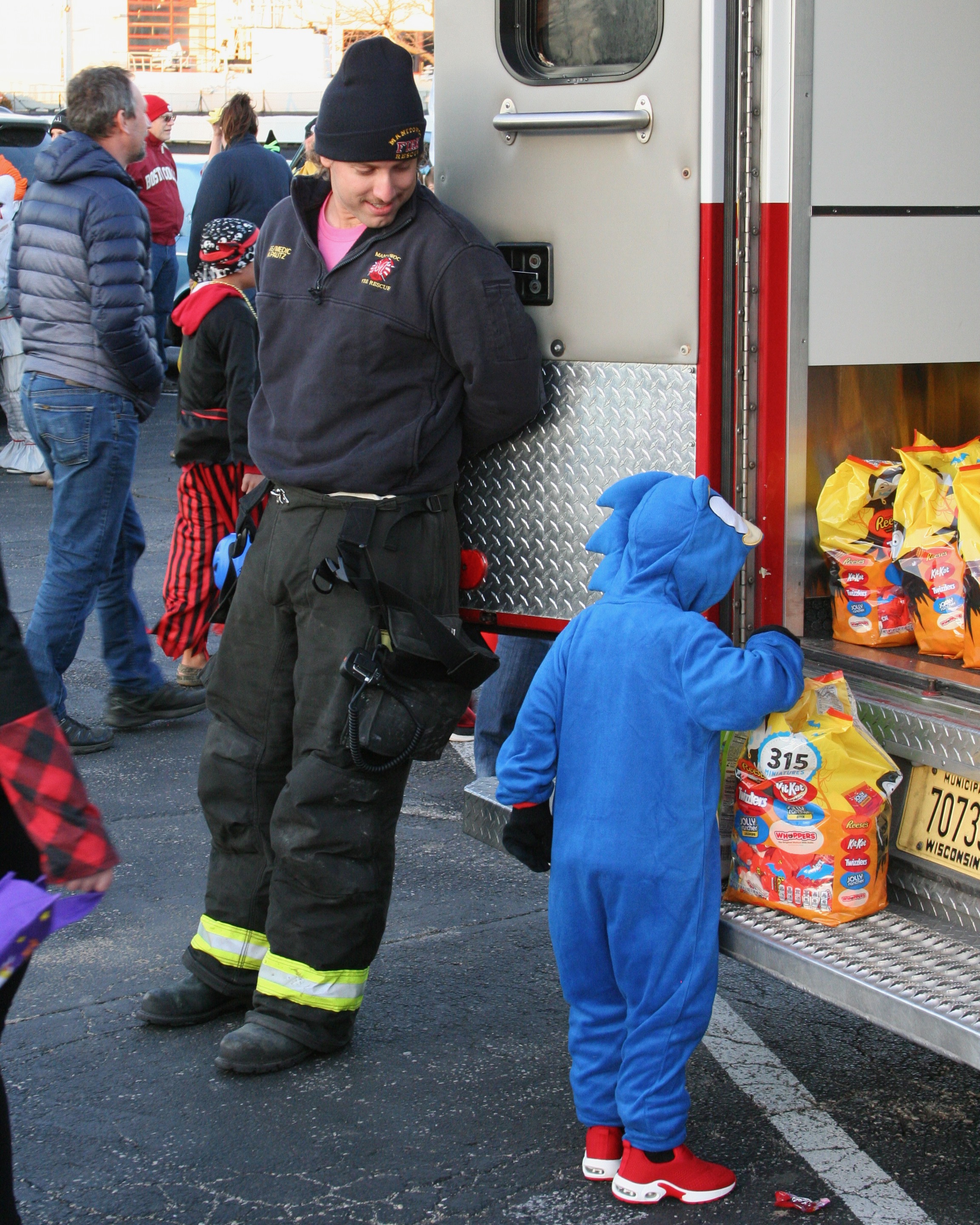 Costumed child getting treats from fire truck