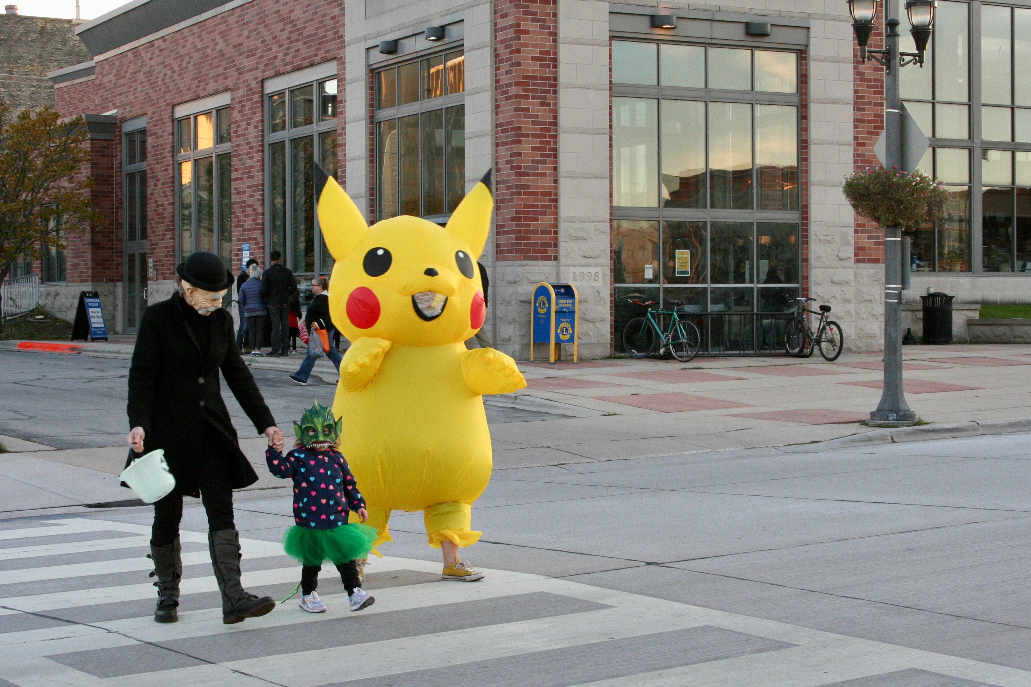 Person wearing inflatable Pikachu costume walks beside adult and child