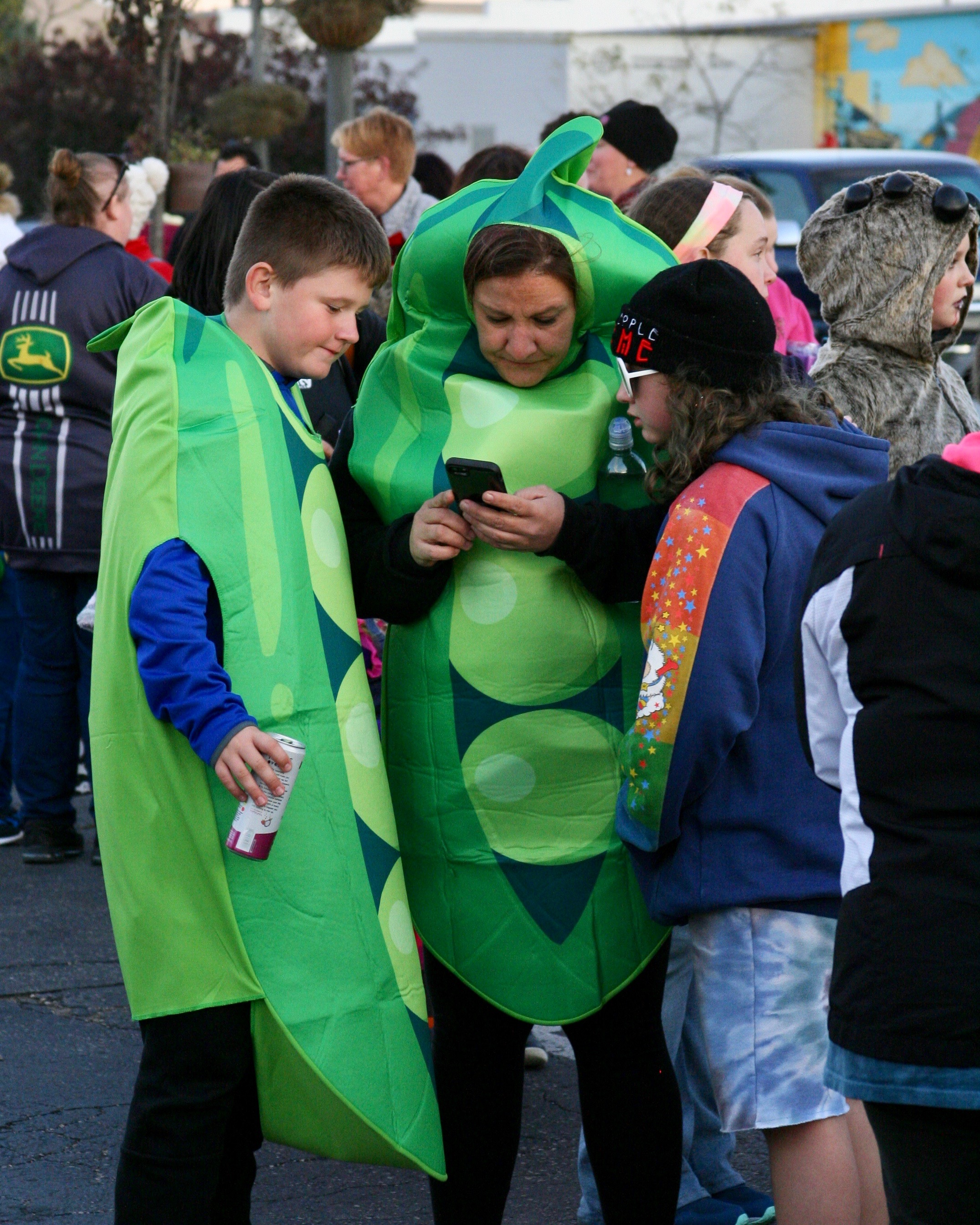 People wearing matching "peas in a pod" costumes looking at phone