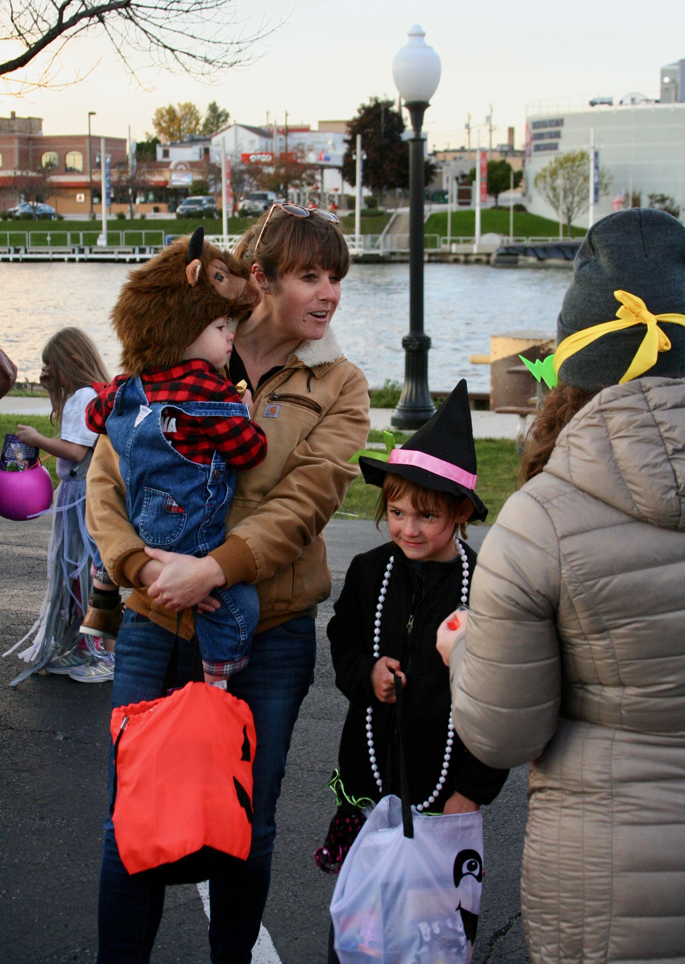 Woman with costumed children speaks with participant handing out treats