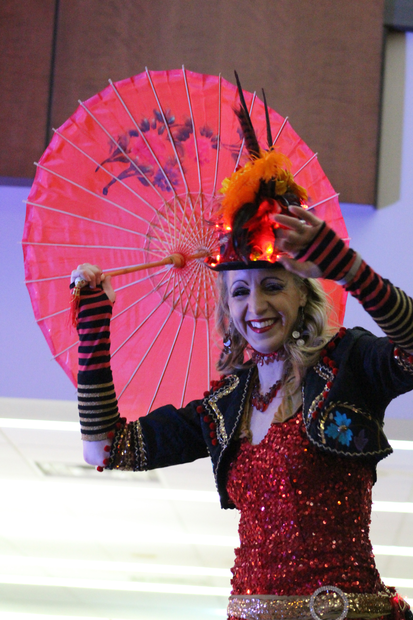 Woman wearing ringleader costume carrying red parasol