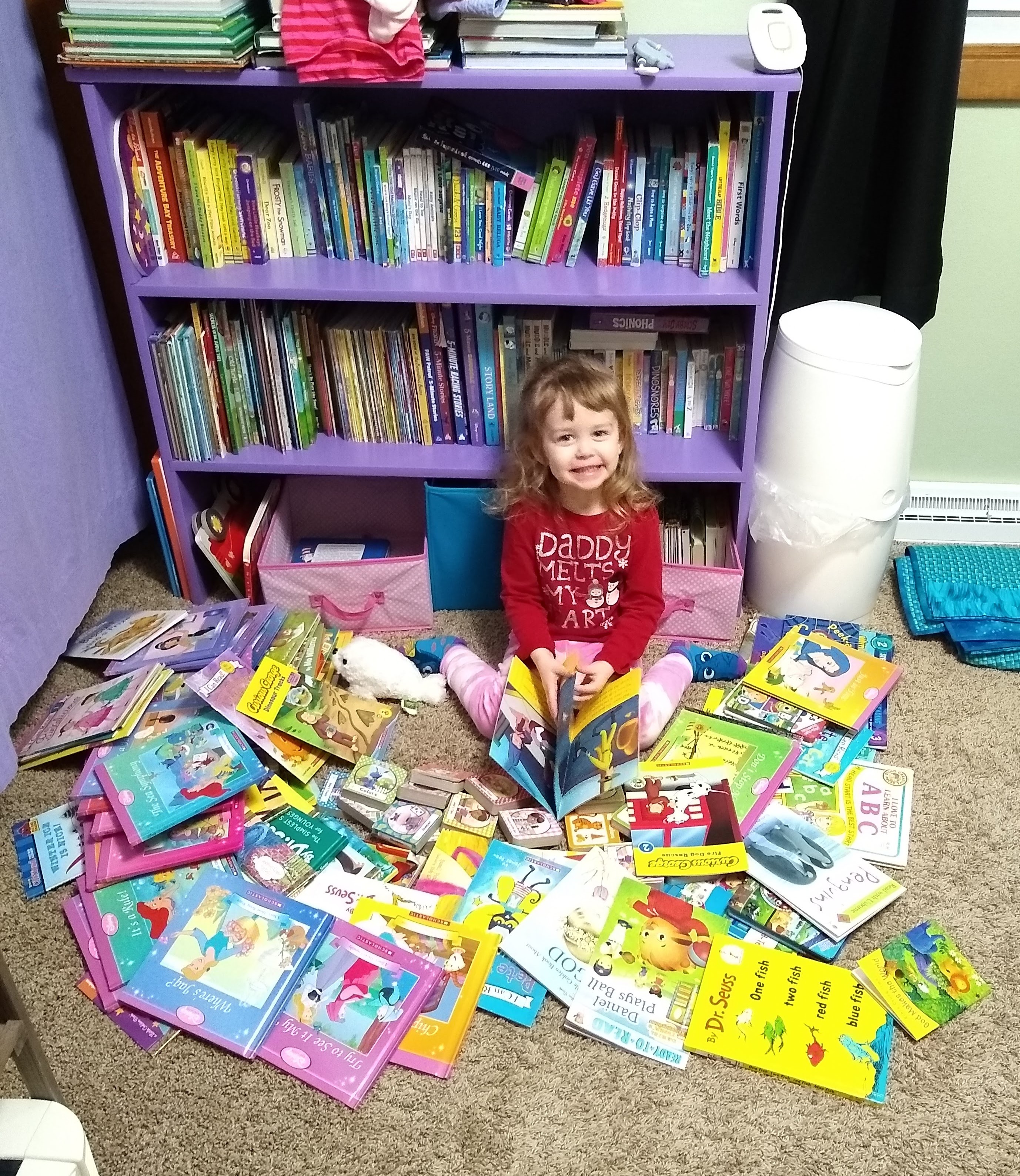 Child surrounded by picture books with shelf in background