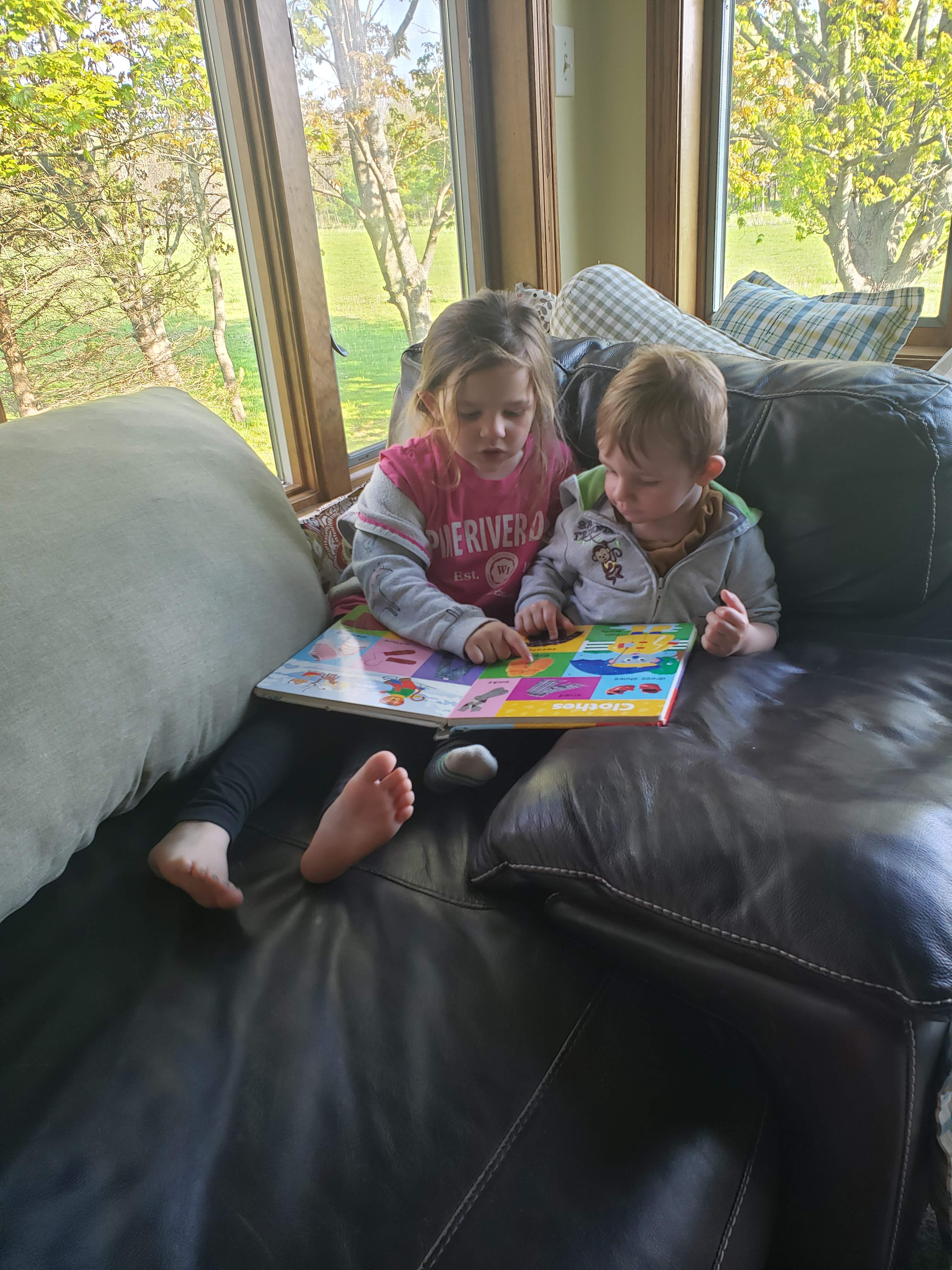 Child reading to younger child on sofa