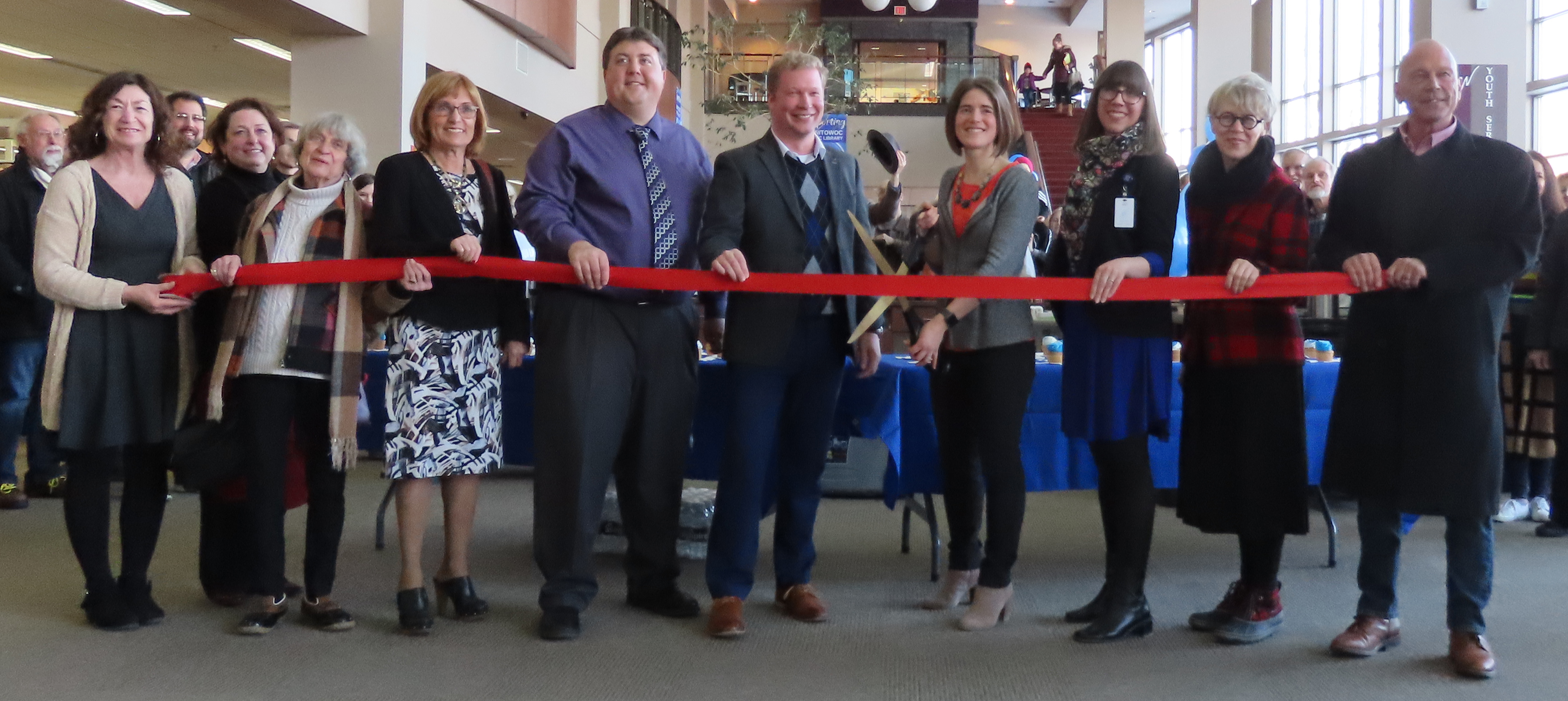 Library officials pose with giant scissors and red ribbon