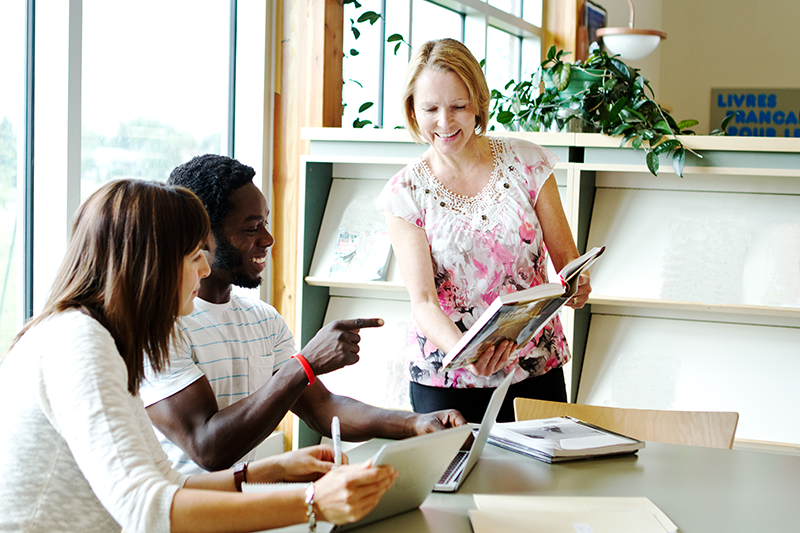 An Outreach Visit image showing a librarian visiting two people with books