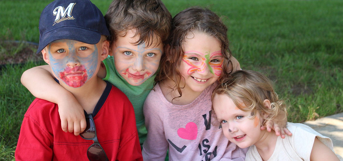 Four children with face paint enjoying the library carnival