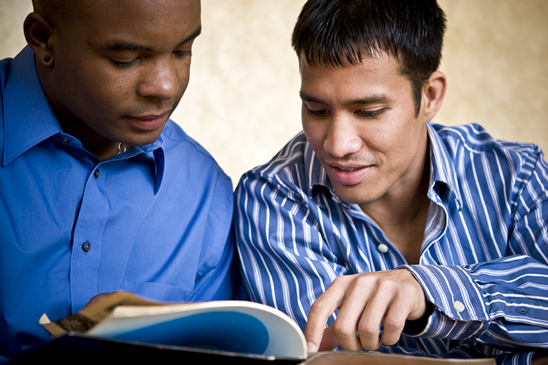 Two men reading a book together as a part of the one-on-one adult literacy program