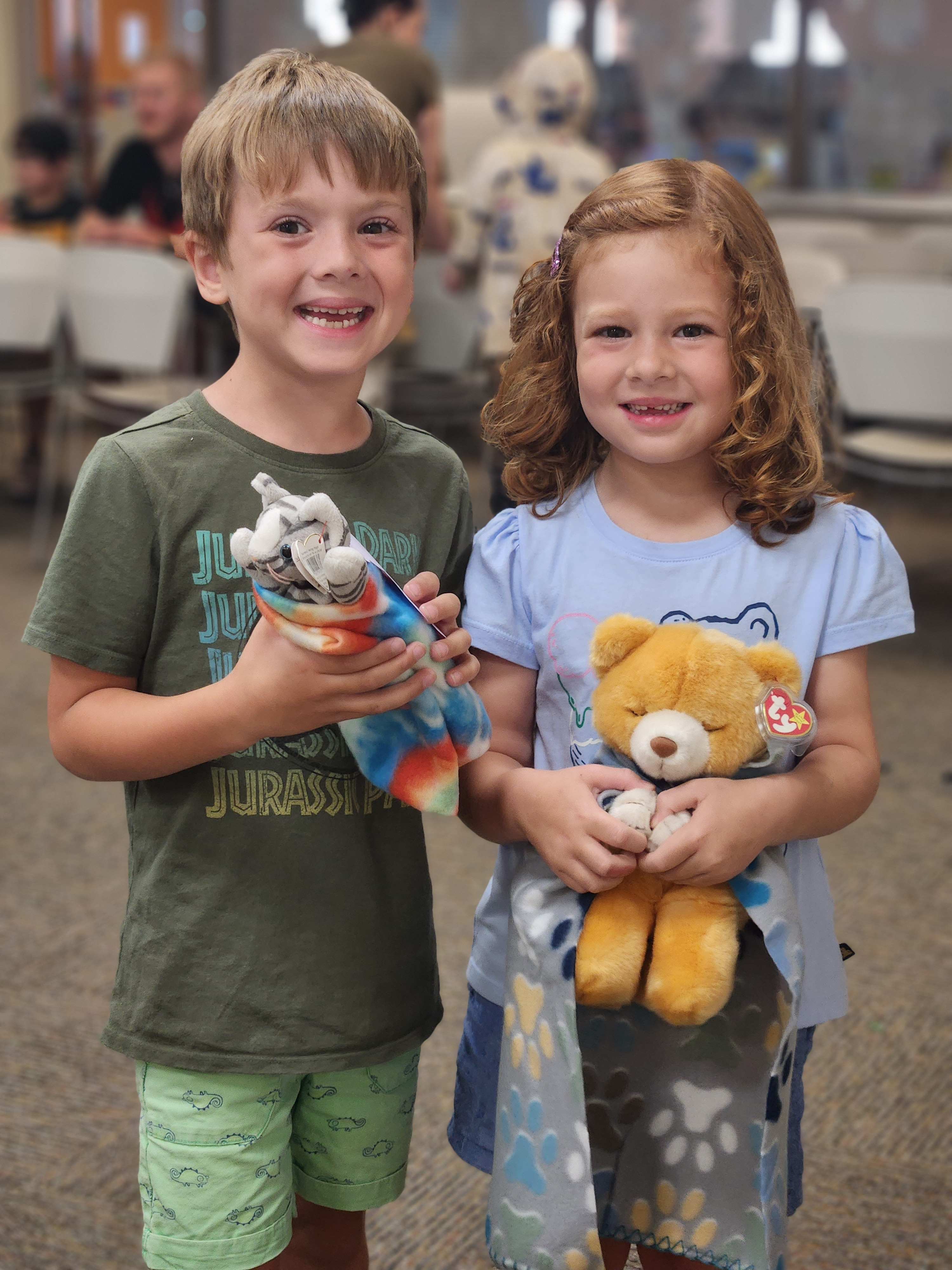 A boy and a girl smiling while holding stuffed animals during the Stuffed Animal Sleepover