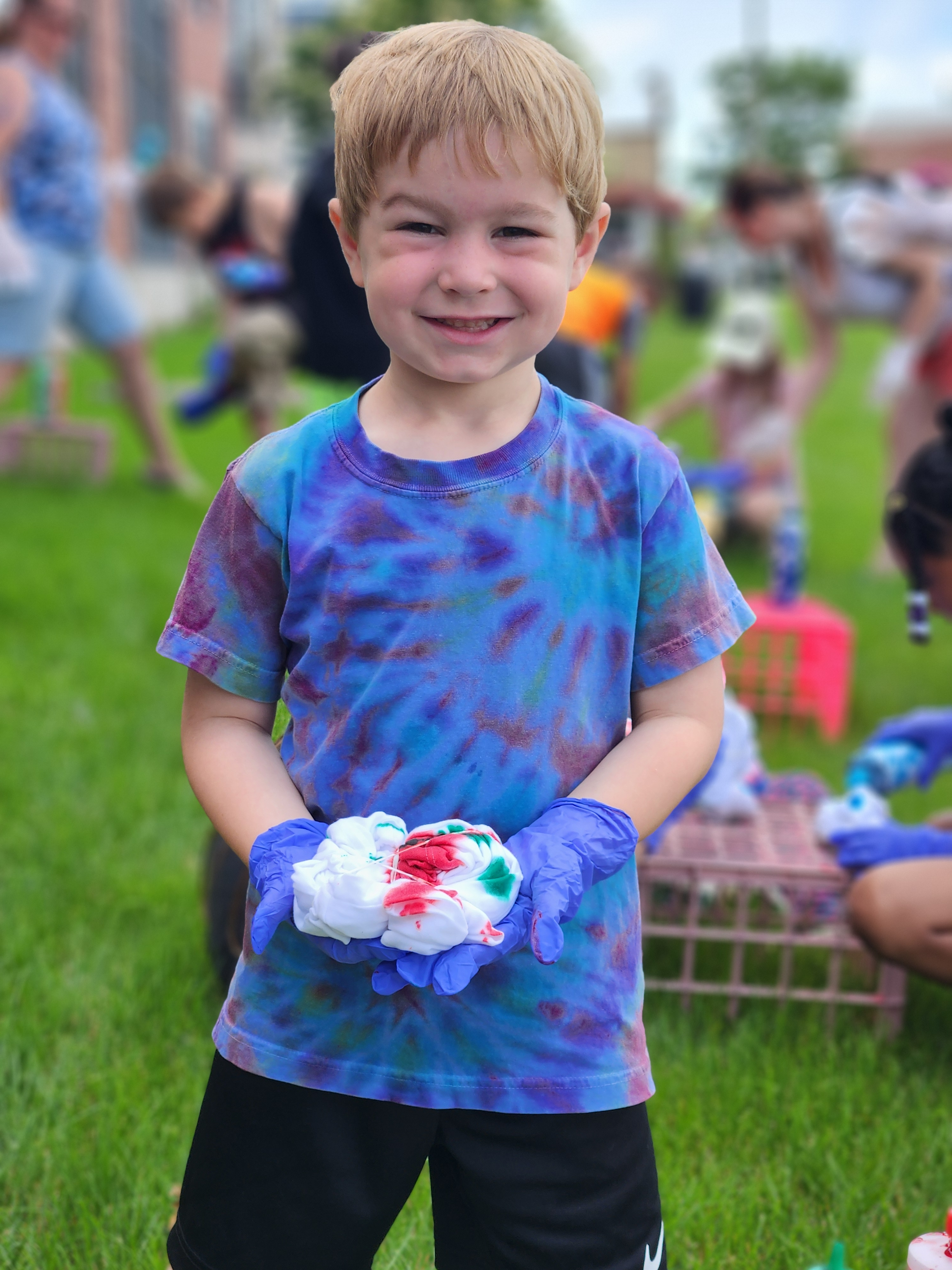 Young boy smiling while wearing a tie dye shirt during the Tie Dye Tuesday event