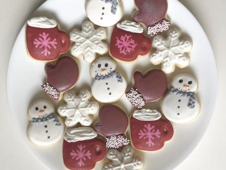 Iced sugar cookies decorated like snowmen, cocoa cups, mittens, and snowflakes