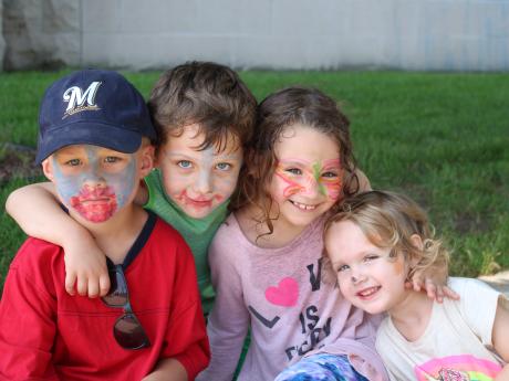 Four children pose together to show off face paint