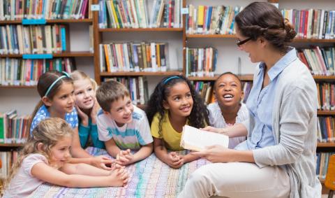 Woman reading book to group of children in a library