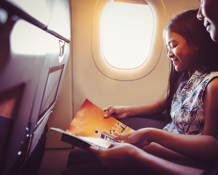Girl and mother on an airplane reading a book